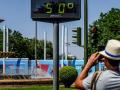 Transeúntes fotografían el termómetro situado en el Prado que marca 50 grados, a 26 de junio del 2023 en Sevilla