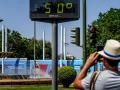 Transeúntes fotografían el termómetro situado en el Prado que marca 50 grados, a 26 de junio del 2023 en Sevilla