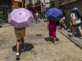 Dos personas caminan con paraguas para resguardarse del calor en Toledo