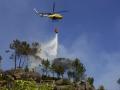 Un helicóptero arroja agua sobre un incendio forestal