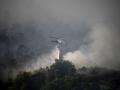Un helicóptero de extinción de incendios arroja agua para extinguir un incendio forestal en Diakopto, Egio, Grecia