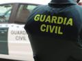 Un agente de la Guardia Civil, de espaldas, junto a un vehículo oficial