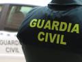 Un agente de la Guardia Civil, de espaldas, junto a un vehículo oficial
