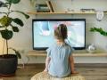 Una niña pequeña frente a un televisor encendido