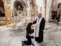 Un sacerdote sirio consuela a una familia cristiana
