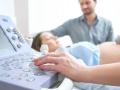 Médico pasando consulta a una mujer embarazada con su marido