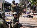Soldados israelíes cerca del cuerpo de un militante palestino en Kfar Aza, en el sur de Israel