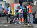 Una trabajadora de la Cruz Roja traslada en silla de ruedas a uno de los migrantes que ha llegado en un cayuco al puerto de La Restinga (El Hierro).