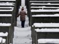 Un visitante camina entre las estelas cubiertas de nieve del monumento al Holocausto mientras nieva en Berlín