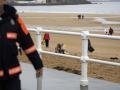Unos voluntarios recogen pélets en la playa de San Lorenzo de Gijón, en Asturias