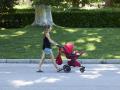 Una mujer pasea con un carrito de bebé en el parque de El Retiro