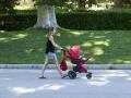 Una mujer pasea con un carrito de bebé en el parque de El Retiro
