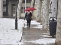 Una mujer sujeta un paraguas mientras camina por una calle de nieve en Jaca, Huesca