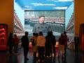 La gente mira un vídeo del presidente chino Xi Jinping en un desfile militar en el Museo del Partido Comunista de China en Pekín