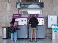 Dos personas compran billetes en los cajeros de venta automática en la estación de tren de Santiago