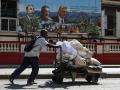 Un hombre empuja una carretilla frente a un mural de los líderes de la dictadura cubana