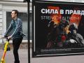 Un hombre pasa en un scooter eléctrico por una exposición callejera de carteles de temática militar en Moscú