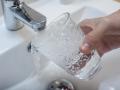 Una persona llena un vaso de agua de un grifo