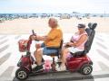 Una pareja pasea en moto eléctrica por el paseo de la playa de Poniente de Benidorm