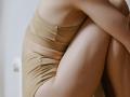 Una mujer hunde su cabeza entre sus piernas.