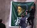 Unos hombres cuelgan un enorme retrato del difunto presidente de Irán, Ebrahim Raisi