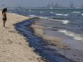 Una persona contempla el vertido de combustible en la playa de El Saler, Valencia