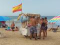 Un vendedor ambulante ofrece a los bañistas bebida fría o fruta fresca en la playa de Costa Ballena en Rota