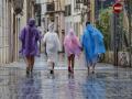 Varias personas caminan bajo la lluvia por una calle del centro de Valencia