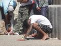 Un inmigrante rescatado se apoya en el suelo durante el rescate de diez menores, de una patera en aguas de Barbate