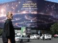 Iraníes caminan y conducen frente a un cartel con una imagen que muestra un ataque con misiles sobre Israel