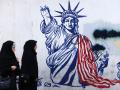 Mujeres iraníes pasan junto a un mural que representa a la Estatua de la Libertad con el brazo que porta la antorcha roto, pintado en las paredes exteriores de la antigua embajada de Estados Unidos, en Teherán
