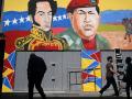 La gente pasa junto a un mural con la imagen del fallecido presidente venezolano Hugo Chávez y del libertador venezolano Simón Bolívar