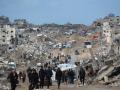 Palestinos desplazados caminan por un camino embarrado en medio de la destrucción en Jabalia, en el norte de la Franja de Gaza