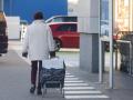 Una mujer sale de un supermercado con un carro de la compra.