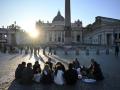 La gente se sienta cerca de la Basílica de San Pedro al atardecer en la Ciudad del Vaticano