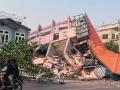 Personas en motocicleta pasan junto a un edificio derrumbado en Mandalay el 28 de marzo de 2025, tras un terremoto en el centro de Myanmar