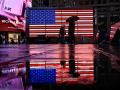 Un grupo de personas pasa junto a una bandera estadounidense en Times Square