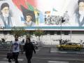 Dos iraníes cruzan una calle cerca de un mural en Teherán, Irán