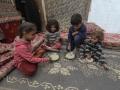 Niños palestinos comen alimentos entregados por una organización caritativa