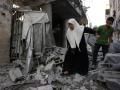 Un niño ayuda a una anciana palestina a caminar entre los escombros