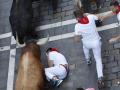 PAMPLONA, 10/07/2025.- Un mozo se intenta proteger tras caer al paso de los toros durante el cuarto encierro de los Sanfermines