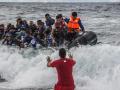Un miembro del equipo de rescate calma a los migrantes en pánico, mientras llegan en un bote de goma sobrecargado a la costa cerca de Skala Sikaminias, isla de Lesbos, Grecia
