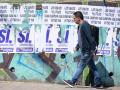 Un hombre pasa junto a una pared con carteles que respaldan el referéndum propuesto por el presidente de Ecuador, Daniel Noboa, en el norte de Quito