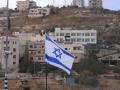 Una bandera de Israel en primer plano y una bandera de Palestina en Nablus, Cisjordania