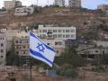 Una bandera de Israel en primer plano y una bandera de Palestina en Nablus, Cisjordania