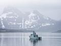 El buque patrullero de la Armada danesa HDMS Ejnar Mikkelsen rodeado de montañas cubiertas de nieve en la entrada de mar que conduce a Nuuk, Groenlandia
