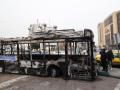 Los restos de un autobús incendiado con una pancarta que dice "Este fue uno de los nuevos autobuses de Teherán, financiado con el dinero de los impuestos del pueblo", en la plaza Sadeghieh de Teherán