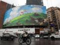 Un ciclista pasa junto a un cartel antiestadounidense en un edificio de la plaza Valiasr de Teherán
