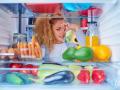 Una mujer mirando su nevera llena de comida