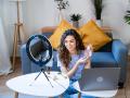 Curly-haired woman showcasing skincare products on camera